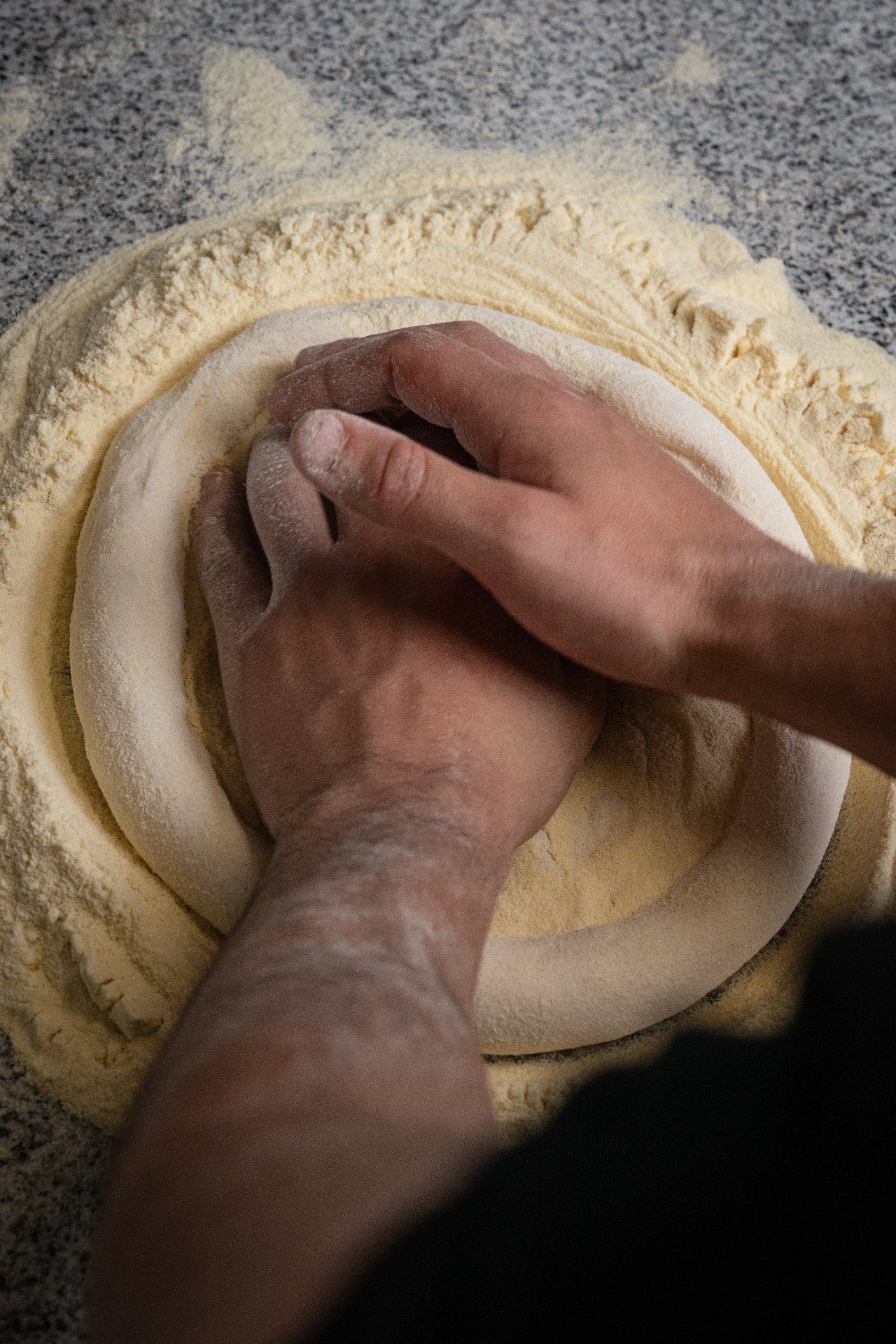 Manos amasando pizza napolitana sobre harina